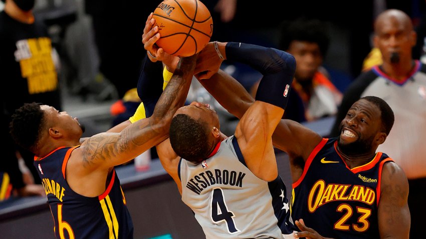 El armador Russell Westbrook intenta capturar un rebote sobre el escolta Kent Bazemore y el delantero fuerte, Draymond Green.